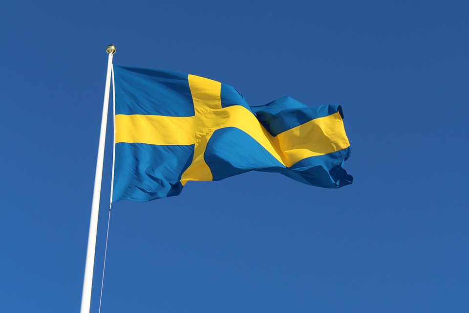 Svenska flaggan med blå himmel i bakgrunden
