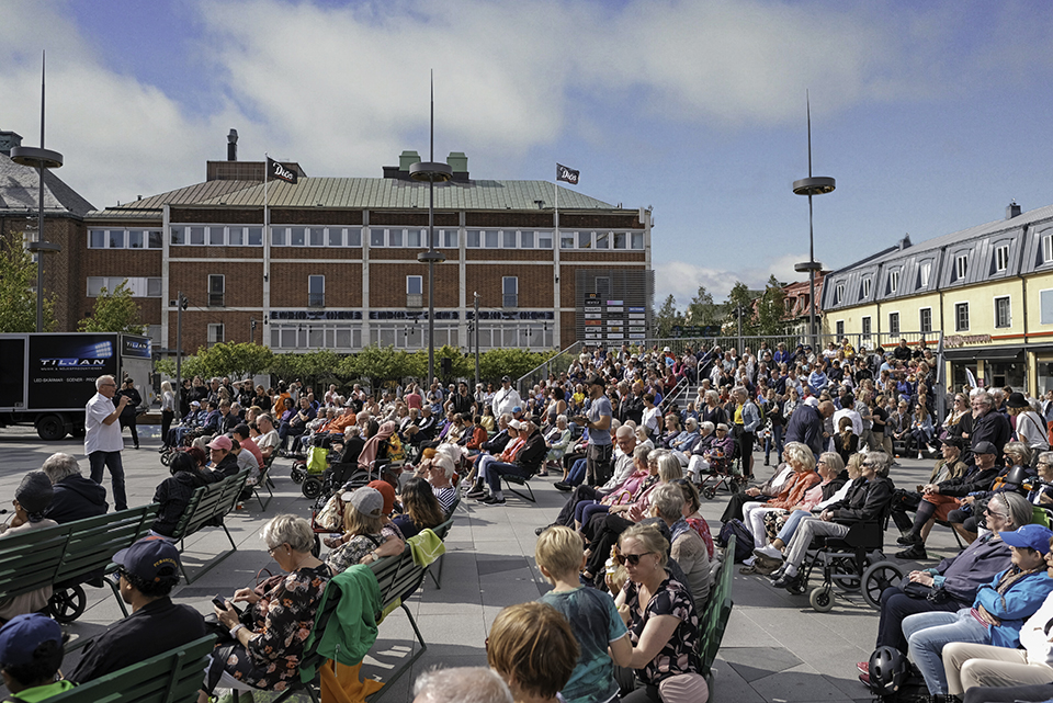 människor sitter på stolar på torget, musikunderhållning