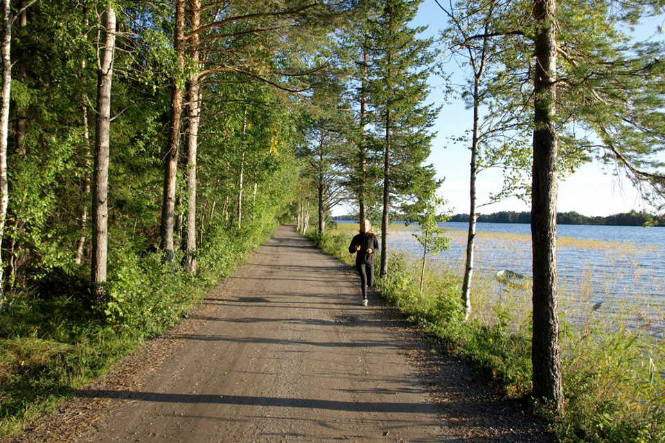 Kvinna springer på en grusväg längs Nydalasjön.