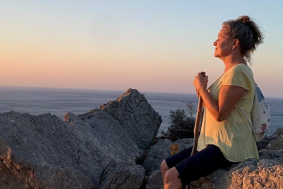 Kvinna sitter på klippa med utsikt över havet