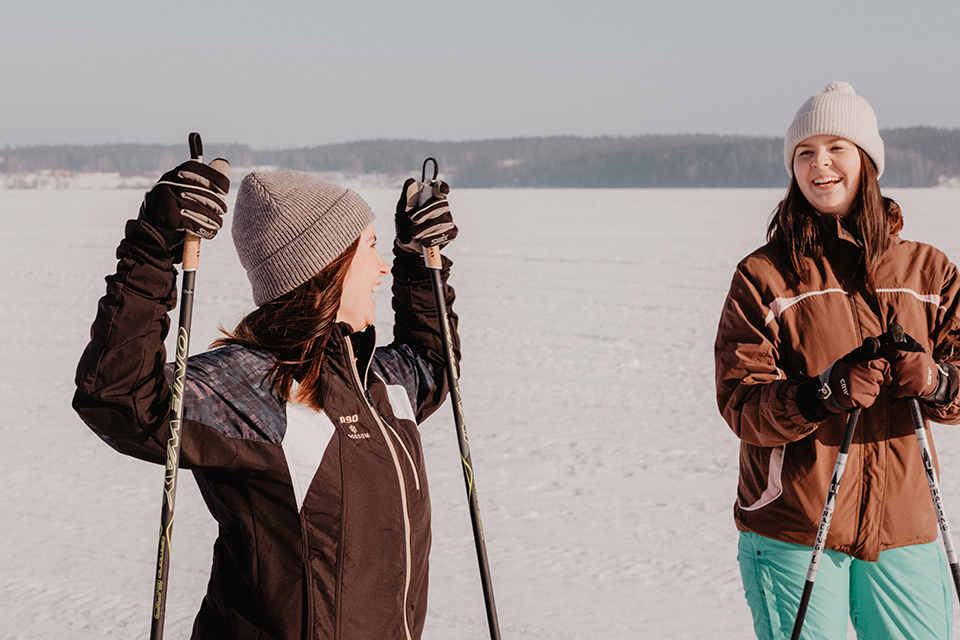 Bilden visar två glada unga kvinnor i vintermiljö