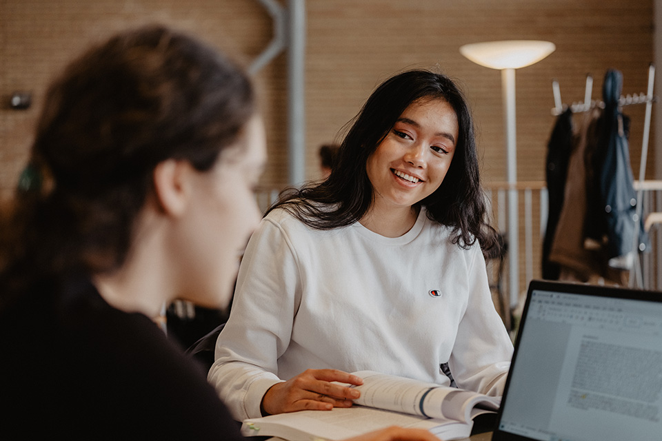 Två studenter pluggar i Lindellhallen och verkar glada.