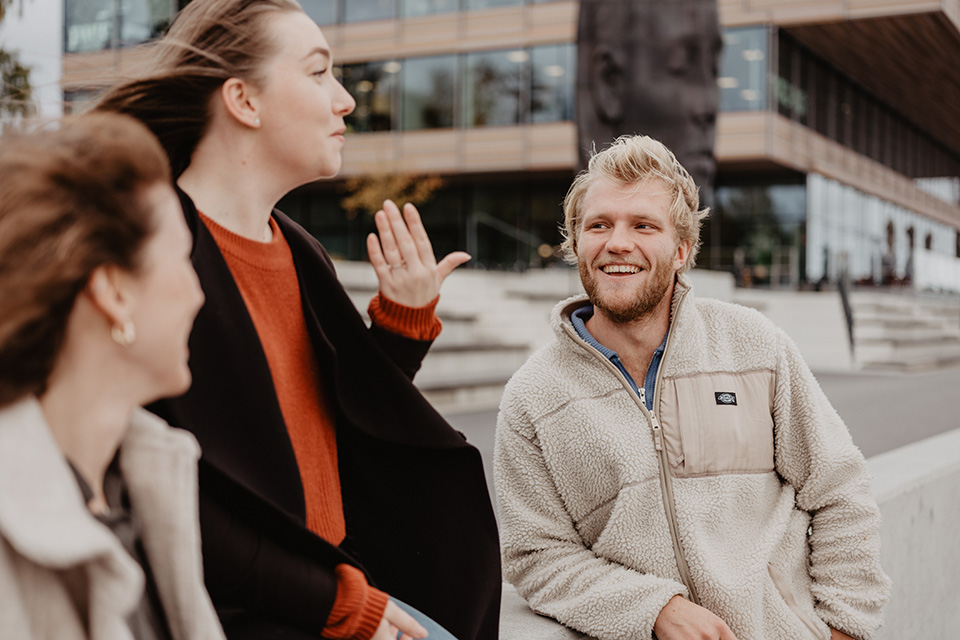 Personer som samtalar utomhus på konstnärligt campus.