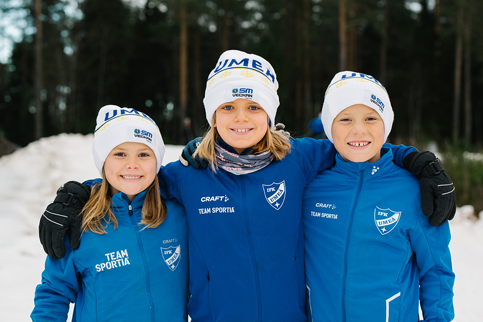Bilden visar tre barn från föreningen IFK Umeå med SM-veckans mössa på huvudet.