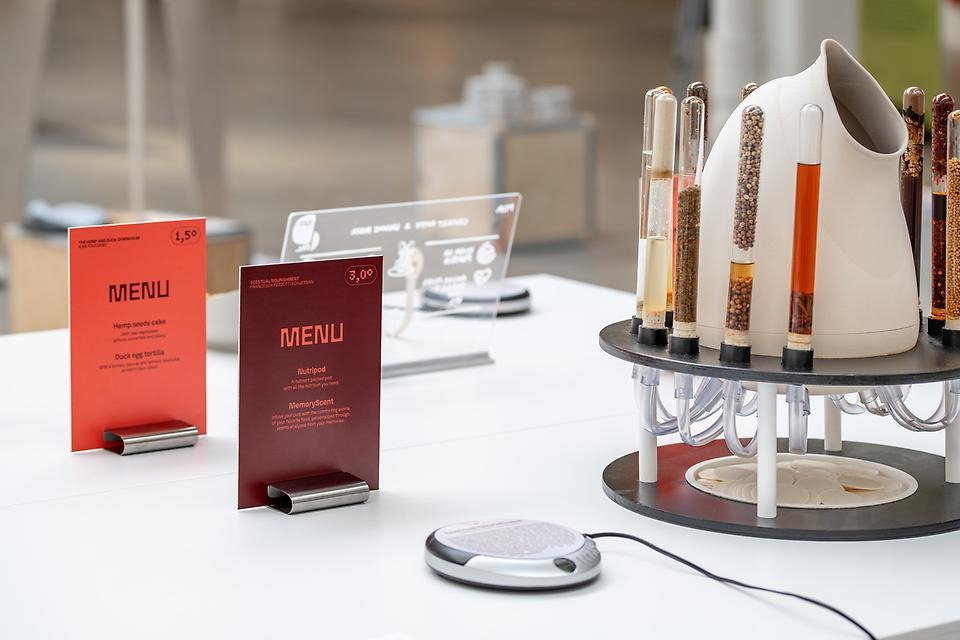 Ett vitt bord med röda menykort och en apparat med provrör fyllda med olika ingredienser.