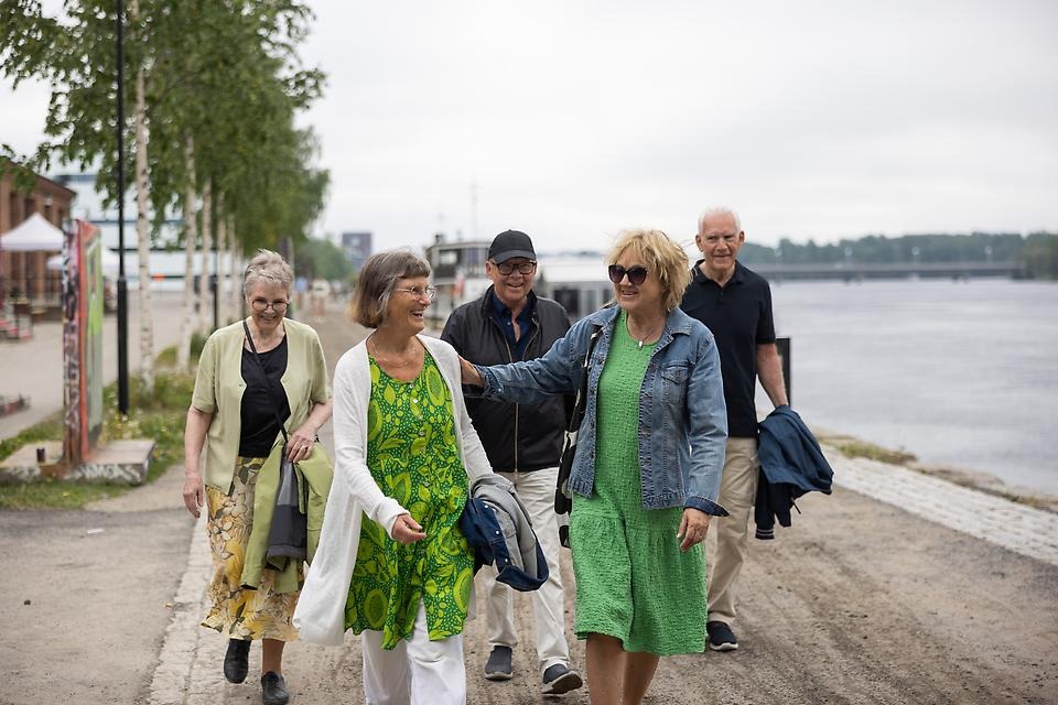 Grupp med kvinnor och män som promenerar längs med strandpromenaden i Umeå