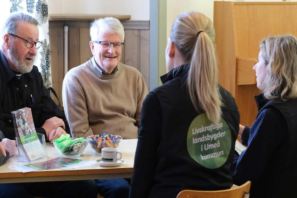 Landsbygdsstrateger möter representanter från någon by över en kopp kaffe.