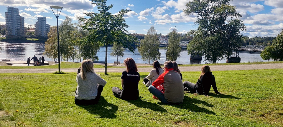 En grupp personer sitter på en gräsmatta.