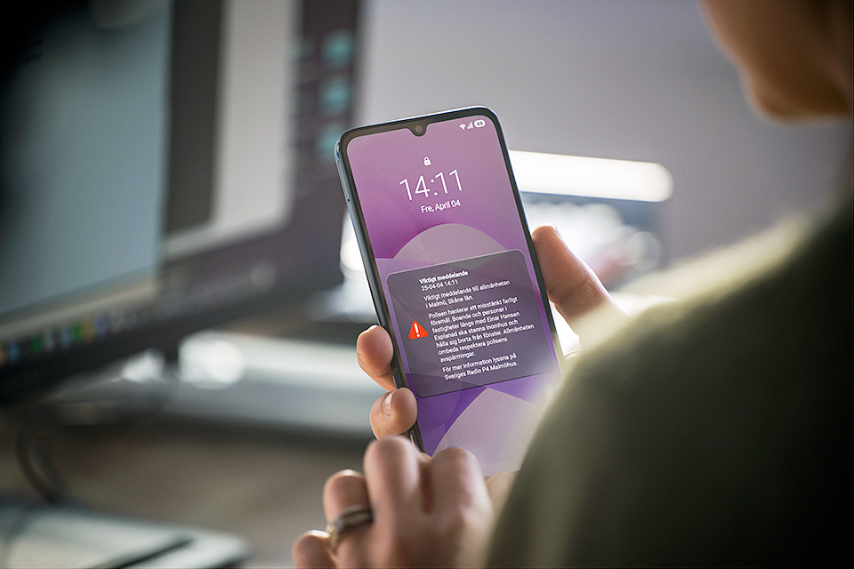 Person håller mobiltelefon som visar meddelande via SE-Alert.