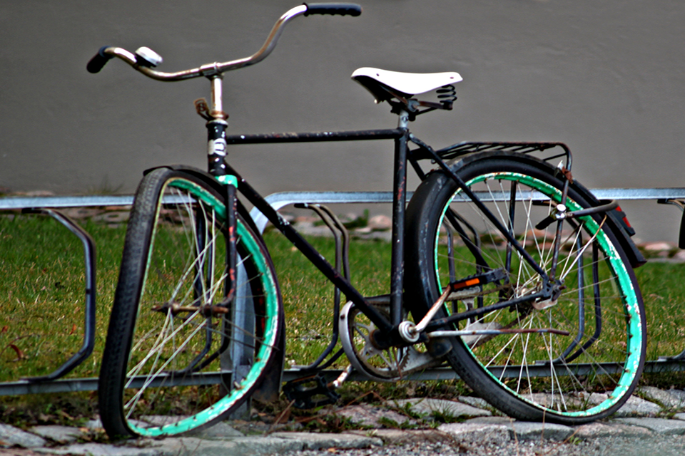 En övergiven och trasig vit cykel, som är fastkedjan vid ett stuprör.