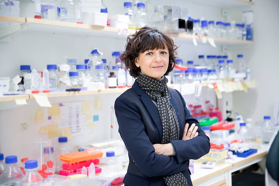 Nobelpristagaren Emmanuelle Charpentier framför skrivbord och hyllor fyllda med små burkar och provrör.