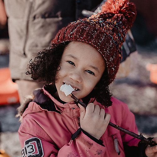 Child with knitted hat eating outdoors