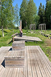 Två boxar i trä och en kvinna som gör situps i bakgrunden.