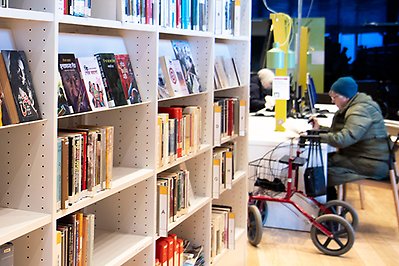 Vy från stadsbiblioteket med bokhylla och besökare